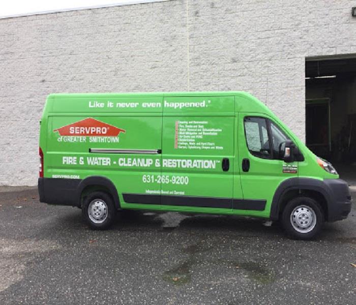 Green SERVPRO van in front of a white brick wall