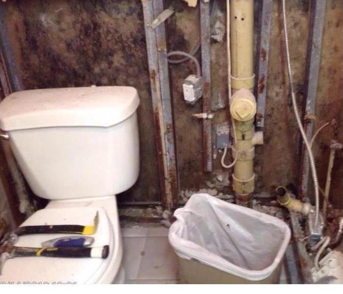Bathroom with toilet and pipes in wall exposed