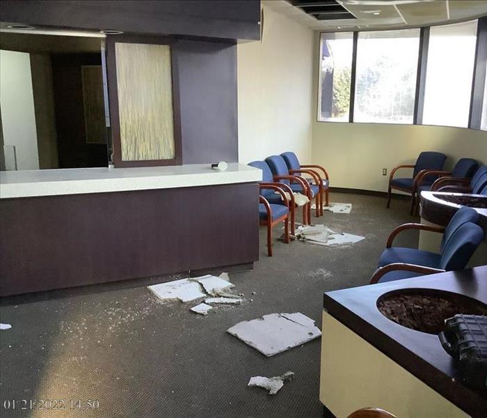 Medical office lobby with collapsed ceiling tiles and signs of water saturation on carpeting 