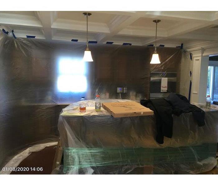 Kitchen with plastic covering and pizza box and drinks on the center island