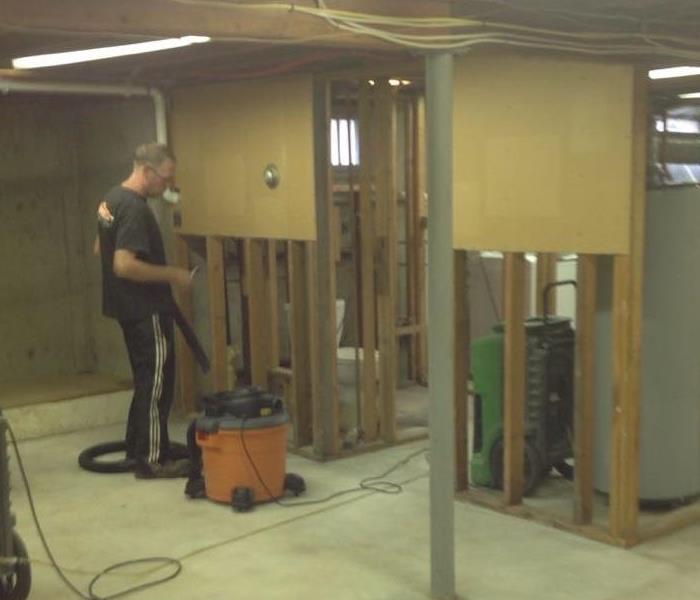 basement with bottom 4 feet of framing exposed and male employee using a shopvac