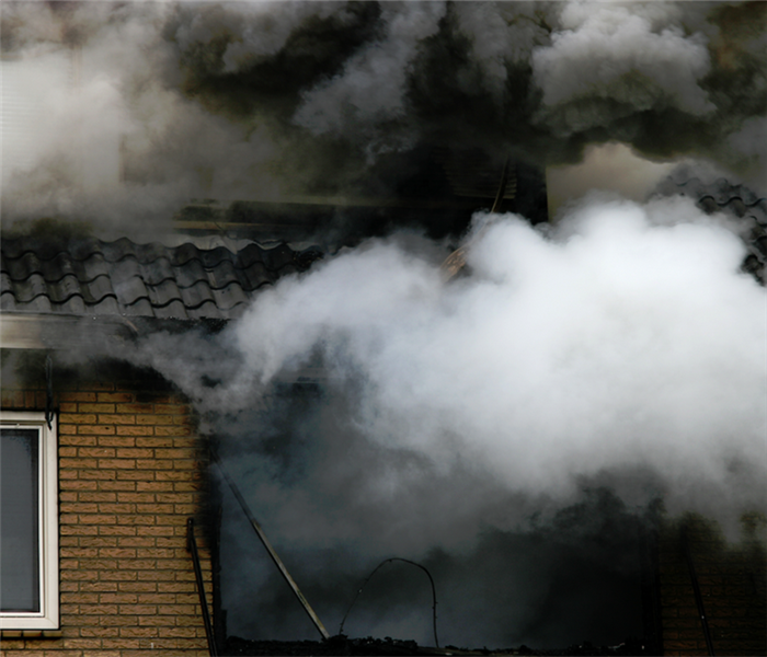 smoke billowing from the windows of a house on fire