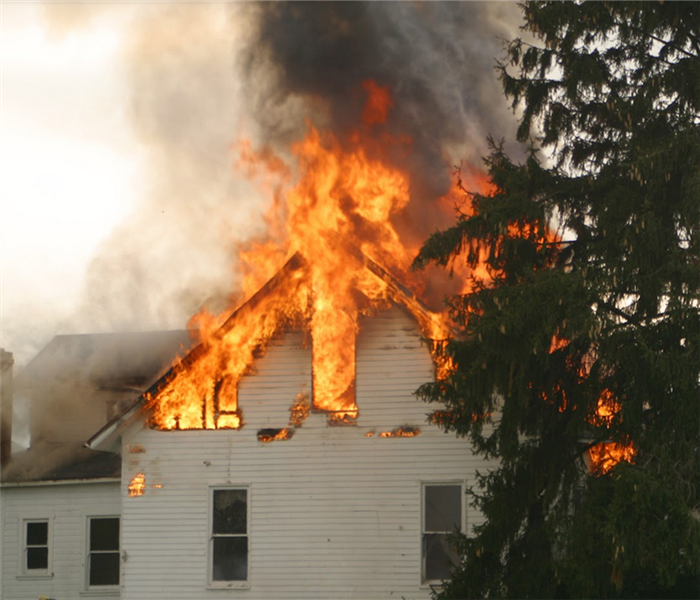 a house with its roof and top floor on fire
