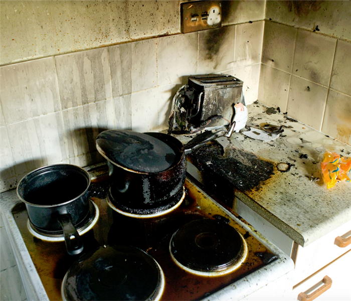 fire damaged kitchen stove with burned pots on top of it